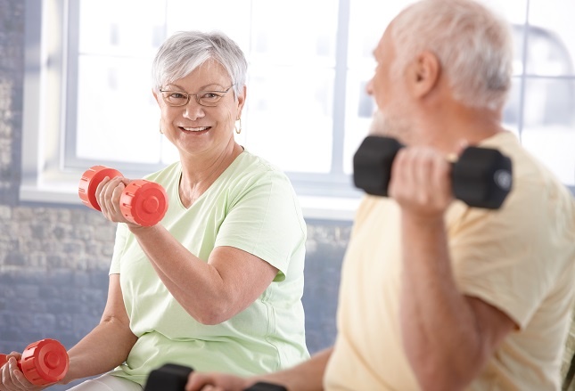 A senior woman and man lifting weights
